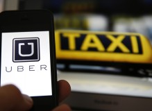 File illustration picture showing the logo of car-sharing service app Uber on a smartphone next to the picture of an official German taxi sign